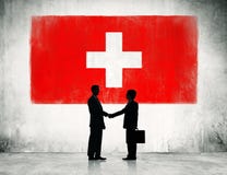 Apretón de manos de los hombres de negocios con la bandera de Suiza foto de archivo libre de regalías Apretón de manos de los hombres de negocios con la bandera de Suiza foto de archivo libre de regalías