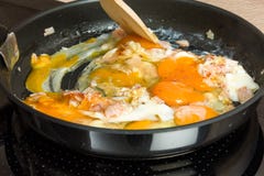 Apronte para o café da manhã: cozinhando ovos mexidos em uma cozinha moderna Imagens de Stock Apronte para o café da manhã: cozinhando ovos mexidos em uma cozinha moderna Imagens de Stock