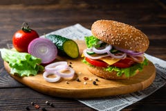 Aptitretande hamburgare med skinka, tomaten, gurkor, ost och grönsallat, slut upp royaltyfri bild Aptitretande hamburgare med skinka, tomaten, gurkor, ost och grönsallat, slut upp royaltyfri bild