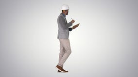 Arabic man in casual clothes and hard hat writing down checklist on gradient background. stock video footage Arabic man in casual clothes and hard hat writing down checklist on gradient background. stock video footage