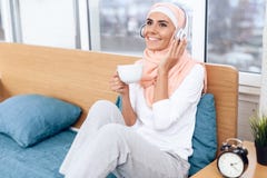 Arabska kobieta pije herbaty i słuchania muzyka podczas gdy siedzący na łóżku obrazy royalty free Arabska kobieta pije herbaty i słuchania muzyka podczas gdy siedzący na łóżku obrazy royalty free