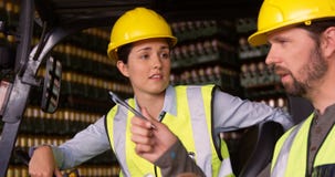 Arbeiders die in vorkheftruck zitten en aan elkaar in pakhuis spreken stock video Arbeiders die in vorkheftruck zitten en aan elkaar in pakhuis spreken stock video