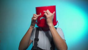 Arbeitskraft in der Uniform mit rotem Eimer auf seinem Kopf traurig stock video footage Arbeitskraft in der Uniform mit rotem Eimer auf seinem Kopf traurig stock video footage