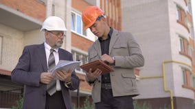 Arbeitskraft mit zwei Geschäften im Sturzhelm besprechend, unter Verwendung der nahen Gestalt der Tablette 4K stock video Arbeitskraft mit zwei Geschäften im Sturzhelm besprechend, unter Verwendung der nahen Gestalt der Tablette 4K stock video