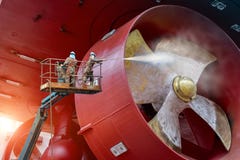 Arbetare på den höga klädersäkerhetsselet under det tvättande propellerskeppet vid strålvattenhögtryck arkivfoton Arbetare på den höga klädersäkerhetsselet under det tvättande propellerskeppet vid strålvattenhögtryck arkivfoton