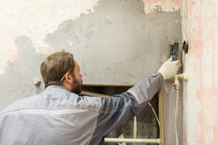 Arbetaren gör att rappa av betongväggen arkivfoto Arbetaren gör att rappa av betongväggen arkivfoto
