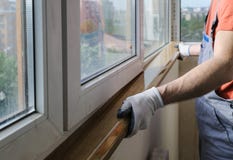 Arbetaren installerar en fönsterfönsterbräda royaltyfri bild Arbetaren installerar en fönsterfönsterbräda royaltyfri bild