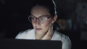 Arbete för exponeringsglas för affärskvinna bärande på en bärbar dator i ett mörkt kontor stock video Arbete för exponeringsglas för affärskvinna bärande på en bärbar dator i ett mörkt kontor stock video
