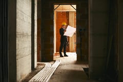 Architect Standing In House Under Construction With Building Plan Stock Photos Architect Standing In House Under Construction With Building Plan Stock Photos