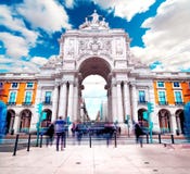 Arco trionfale nel quadrato di commercio al tramonto con il sole e le nuvole immagine stock libera da diritti Arco trionfale nel quadrato di commercio al tramonto con il sole e le nuvole immagine stock libera da diritti