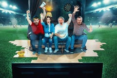 Ardent fans are sitting on the sofa and watching TV in the middle of a football field. stock photography Ardent fans are sitting on the sofa and watching TV in the middle of a football field. stock photography