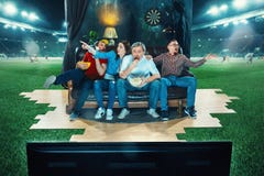 Ardent fans are sitting on the sofa and watching TV in the middle of a football field. stock photography Ardent fans are sitting on the sofa and watching TV in the middle of a football field. stock photography