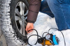 Aria di riempimento in una gomma di automobile Inverno Primo piano di una riparazione del compressore di uso della gomma piana fotografia stock Aria di riempimento in una gomma di automobile Inverno Primo piano di una riparazione del compressore di uso della gomma piana fotografia stock