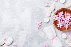 Aromatherapy, beauty, spa background with massage pebble, perfumed flowers water and candles on stone table top view. Flat lay.