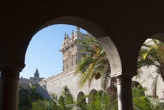 Arquitetura espanhola Vista através dos arcos do palácio nas palmas jardine em um dia ensolarado fotografia de stock Arquitetura espanhola Vista através dos arcos do palácio nas palmas jardine em um dia ensolarado fotografia de stock