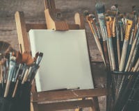 Artistiek materiaal: kunstenaarscanvas op schildersezel en verfborstels stock afbeelding Artistiek materiaal: kunstenaarscanvas op schildersezel en verfborstels stock afbeelding