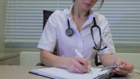 Arts die een voorschrift schrijven bij bureau stock footage Arts die een voorschrift schrijven bij bureau stock footage