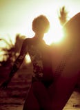 Arty silhouet met de gloed van de zonlens van het jonge gelukkige en aantrekkelijke surfermeisje het dragen brandingsraad stellen royalty-vrije stock afbeelding Arty silhouet met de gloed van de zonlens van het jonge gelukkige en aantrekkelijke surfermeisje het dragen brandingsraad stellen royalty-vrije stock afbeelding