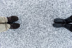As botas masculinas e fêmeas que estão no asfalto cobriram a superfície corajoso da neve Nevado áspero Textplace Inverno frio Vis Foto de Stock Royalty Free As botas masculinas e fêmeas que estão no asfalto cobriram a superfície corajoso da neve Nevado áspero Textplace Inverno frio Vis Foto de Stock Royalty Free