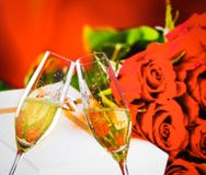 As flautas de Champagne com bolhas douradas em rosas do casamento florescem o fundo imagens de stock As flautas de Champagne com bolhas douradas em rosas do casamento florescem o fundo imagens de stock
