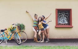 As meninas chiques do boho feliz levantam com as bicicletas perto da fachada da casa fotografia de stock royalty free As meninas chiques do boho feliz levantam com as bicicletas perto da fachada da casa fotografia de stock royalty free