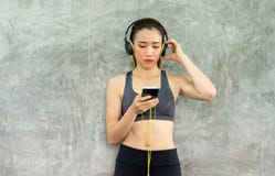 As mulheres do ajuste que usam o Internet esperto da conexão do telefone com fones de ouvido e escutando a música ao sentar-se co imagem de stock As mulheres do ajuste que usam o Internet esperto da conexão do telefone com fones de ouvido e escutando a música ao sentar-se co imagem de stock