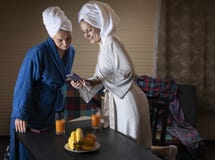 As mulheres na roupa da casa bebem o suco fotografia de stock As mulheres na roupa da casa bebem o suco fotografia de stock