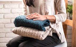 As mãos da mulher que guardam a roupa feita malha Fim acima imagem de stock As mãos da mulher que guardam a roupa feita malha Fim acima imagem de stock