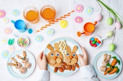 As mãos das crianças com panquecas, doces e suco para a Páscoa fotografia de stock As mãos das crianças com panquecas, doces e suco para a Páscoa fotografia de stock