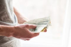 As mãos do homem com dólares no fundo branco Conceito financeiro do negócio giva um subôrno foto de stock As mãos do homem com dólares no fundo branco Conceito financeiro do negócio giva um subôrno foto de stock
