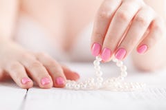 As pérolas brancas nas mãos fêmeas, com pregos pintaram o rosa imagens de stock royalty free As pérolas brancas nas mãos fêmeas, com pregos pintaram o rosa imagens de stock royalty free