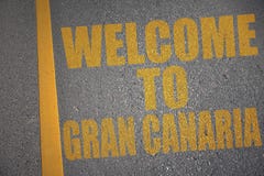 asfaltväg med textvälkomnande till granen canaria nära gul linje Royaltyfri Bild asfaltväg med textvälkomnande till granen canaria nära gul linje Royaltyfri Bild