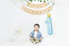 Asian baby boy celebrating first birthday,Cake for 1 year.Infant, small cute child dressed in t-shirt and blue shirt sitting on th
