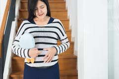 Asian beautiful pregnant woman standing with hand holding her belly at home,Happy mood and positive thinking,Motherhood stock images Asian beautiful pregnant woman standing with hand holding her belly at home,Happy mood and positive thinking,Motherhood stock images