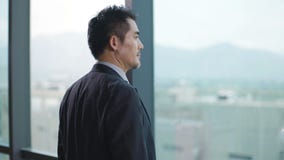 Asian businessman standing in front of windows in office
