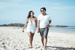 Asian Couple Walking On The Beach Of Tropical Bali Island, Indonesia. Stock Photos Asian Couple Walking On The Beach Of Tropical Bali Island, Indonesia. Stock Photos