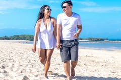 Asian Couple Walking On The Beach Of Tropical Bali Island, Indonesia. Stock Image Asian Couple Walking On The Beach Of Tropical Bali Island, Indonesia. Stock Image