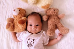 Asian cute baby newborn smile and happy, good mood, on the bed with Teddy bear stock photography Asian cute baby newborn smile and happy, good mood, on the bed with Teddy bear stock photography