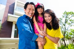 Asian family with child standing in front of home