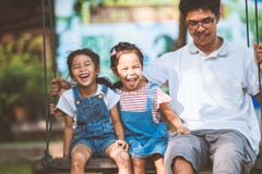 Asian father and daughter having fun to ride on swings together in playground royalty free stock image Asian father and daughter having fun to ride on swings together in playground royalty free stock image