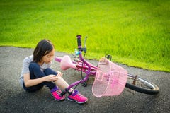 Asian little girl sitting down on the road with a leg pain due to a bicycle accident,the bike fall near the child,girl riding a stock photo Asian little girl sitting down on the road with a leg pain due to a bicycle accident,the bike fall near the child,girl riding a stock photo