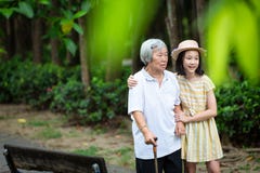 Asian little girl supporting senior woman with walking stick,happy smiling grandmother and granddaughter in the park,elderly royalty free stock photos Asian little girl supporting senior woman with walking stick,happy smiling grandmother and granddaughter in the park,elderly royalty free stock photos
