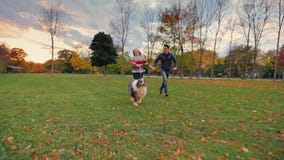 Asian Man And Caucasian Woman Running In The Park With His Dog. Happy Together, Laughing Stock Photos