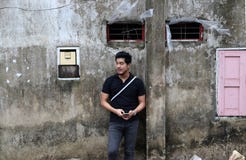 Asian man in black shirt and mobile phone in hand standing on old wall. stock image Asian man in black shirt and mobile phone in hand standing on old wall. stock image