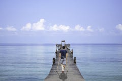 Asian man used wooden crutches walks on bridge pier boat in the sea and the bright sky at Koh Kood, Trat in Thailand stock photos Asian man used wooden crutches walks on bridge pier boat in the sea and the bright sky at Koh Kood, Trat in Thailand stock photos