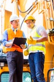 Asian mechanic with construction machine Royalty Free Stock Image Asian mechanic with construction machine Royalty Free Stock Image