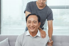 Asian old man shoulder pain, sitting on sofa , son massaging father shoulder royalty free stock image Asian old man shoulder pain, sitting on sofa , son massaging father shoulder royalty free stock image
