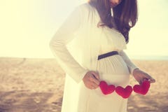 Asian pregnant woman holding heart shape accessories