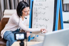 Asian school young woman teacher working from home teach online math subject to student studying from home. Girl points on whitebo
