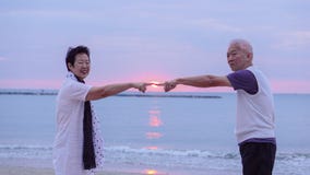Asian senior couple together at sunrise beach. New year, new cha Stock Photos Asian senior couple together at sunrise beach. New year, new cha Stock Photos